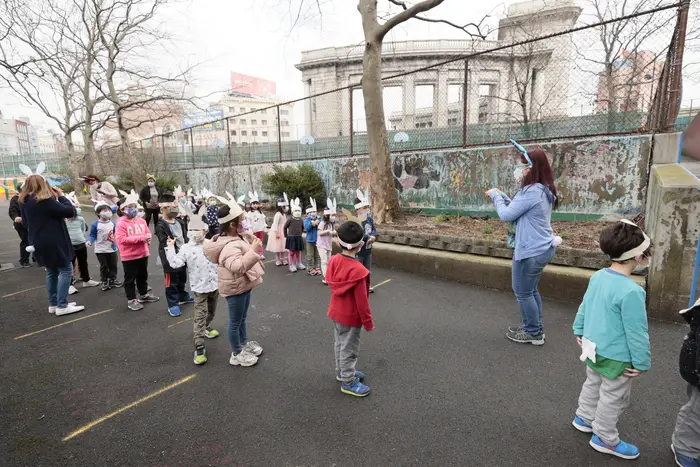 Teacher Samantha Ng (2nd right) assists K and Pre-K students in a bunny hop in the schoolyard at Yung Wing School P.S. 124 on March 25, 2021 in New York City.